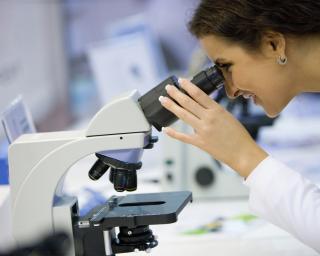Female Scientist looking through a microscope, selective focus.