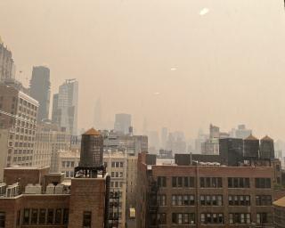 a color photo of a city skyline obscured by smoke from wildfires