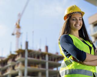 Young female engineer smiling at construction site - stock photo