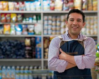 Grocery store owner with arms folded smiling