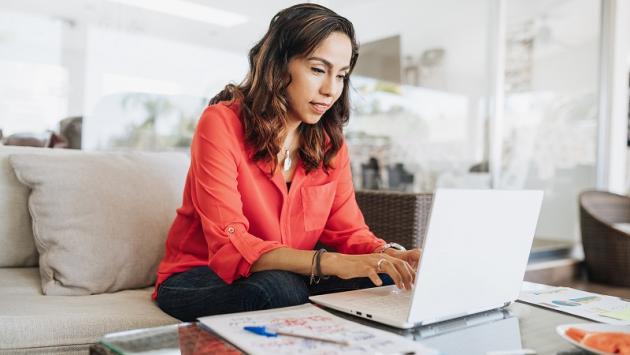 a color stock photo of a brown woman with brown hair, working at a laptop